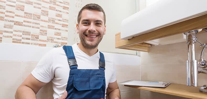 Lächelnder Handwerker vor einem Waschbecken
